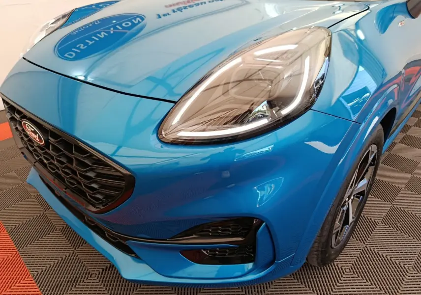Vue 3/4 avant droit du Ford Puma bleu 2025, mettant en valeur son phare LED et sa calandre noire sportive.