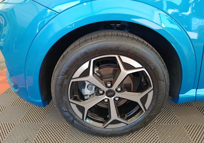 Gros plan sur la roue avant gauche du Ford Puma bleu 2025 avec jante alliage et logo Ford visible.