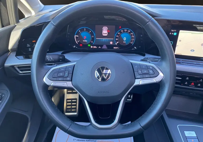 Vue centrée sur le volant cuir multifonction noir de la Volkswagen Golf VIII avec tableau de bord digital et écran tactile.