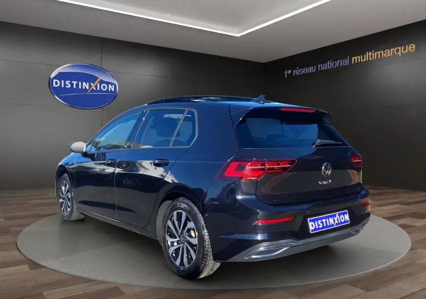 Vue 3/4 arrière droite d'une Volkswagen Golf VIII noire avec toit panoramique et jantes alu 16 pouces.