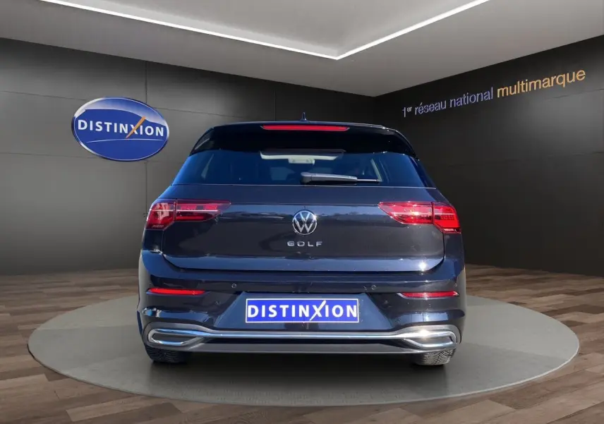 Vue arrière d'une Volkswagen Golf VIII noire intense nacrée, avec feux LED et attelage escamotable visible.