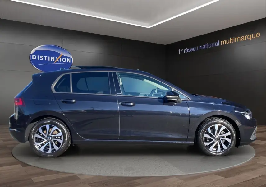 Vue de profil côté gauche d’une Volkswagen Golf VIII noire nacrée avec jantes alu 16 pouces dans un showroom.