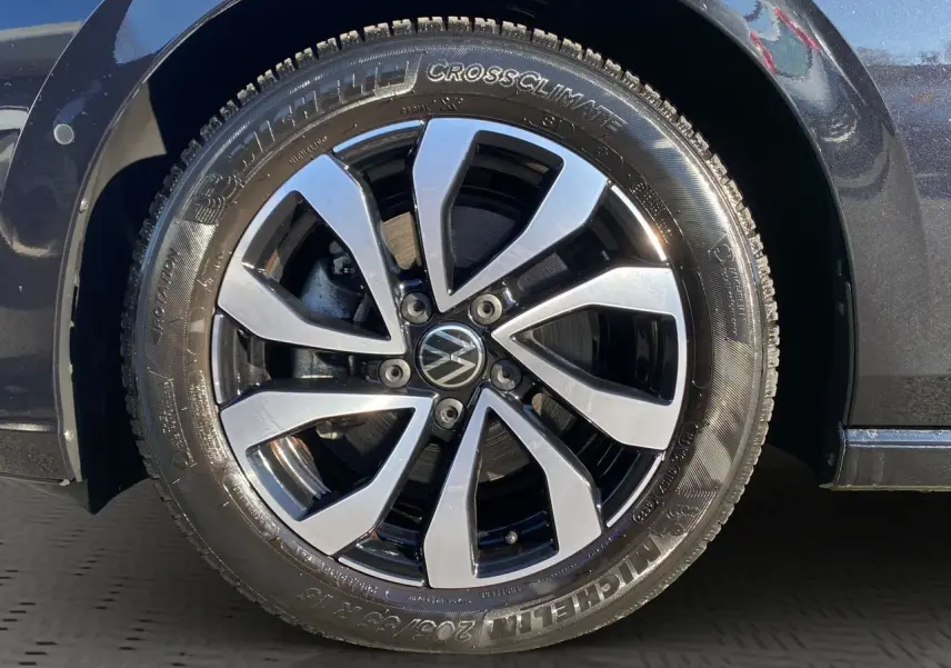Gros plan sur la jante alu 16 pouces bicolore et pneu Michelin CrossClimate du côté avant droit d'une Volkswagen Golf noire.