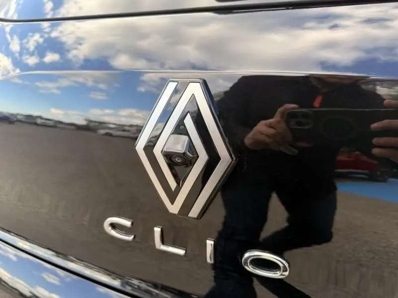 Gros plan sur le logo Renault et l’inscription Clio sur la malle arrière noire brillante d’une Clio V.