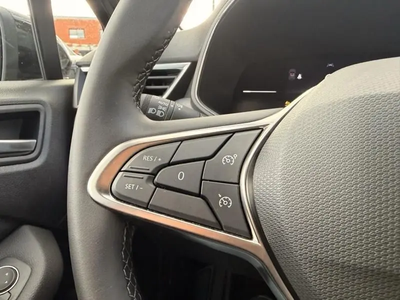 Gros plan sur les commandes au volant côté gauche de la Renault Clio V noire 2025, avec boutons de régulateur de vitesse.