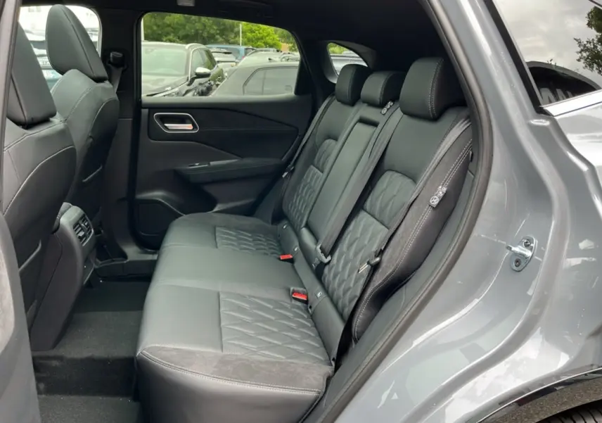 Vue intérieure côté droit sur la banquette arrière cuir noire avec surpiqûres du Nissan Qashqai gris argile 2026.