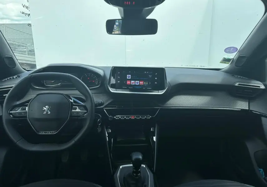 Vue intérieure avant du Peugeot 2008 gris clair 2022 avec tableau de bord carbone et écran tactile 7 pouces.