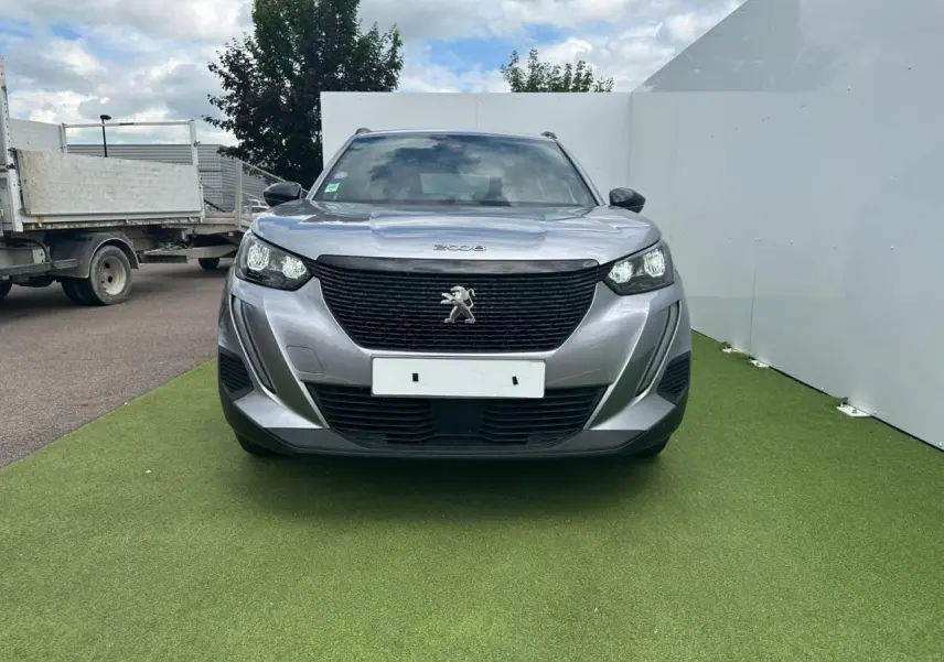 Peugeot 2008 gris clair vue de face, avec calandre noire et logo lion central bien visible.