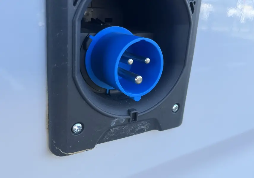 Gros plan sur la prise électrique bleue encastrée dans la carrosserie blanche glacée du Toyota Proace City 2023.