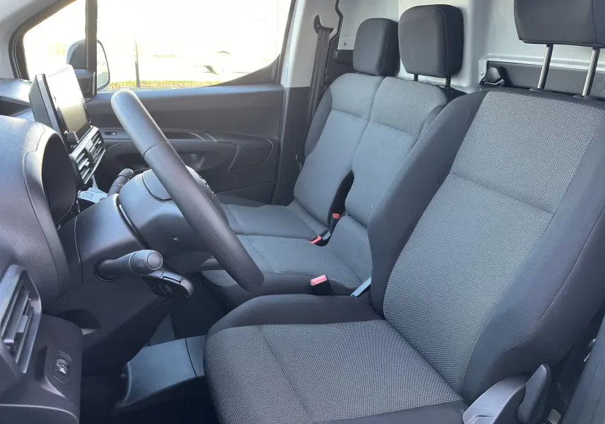 Vue intérieure côté conducteur du Toyota Proace City 2023, sièges tissu gris et tableau de bord moderne.