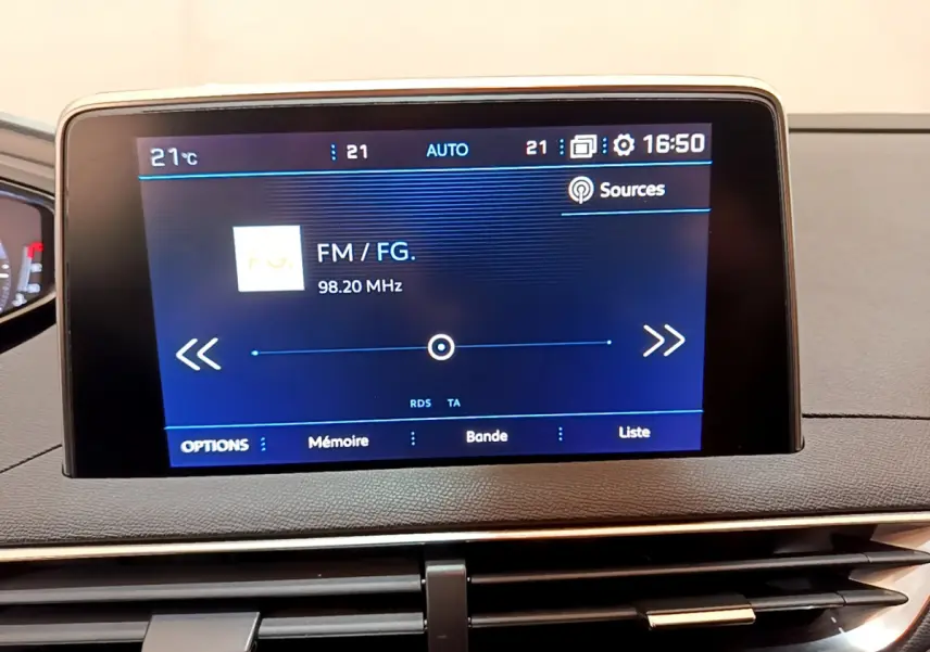 Écran tactile central affichant la radio FM dans l'habitacle du Peugeot 3008 noir, vue rapprochée du tableau de bord.