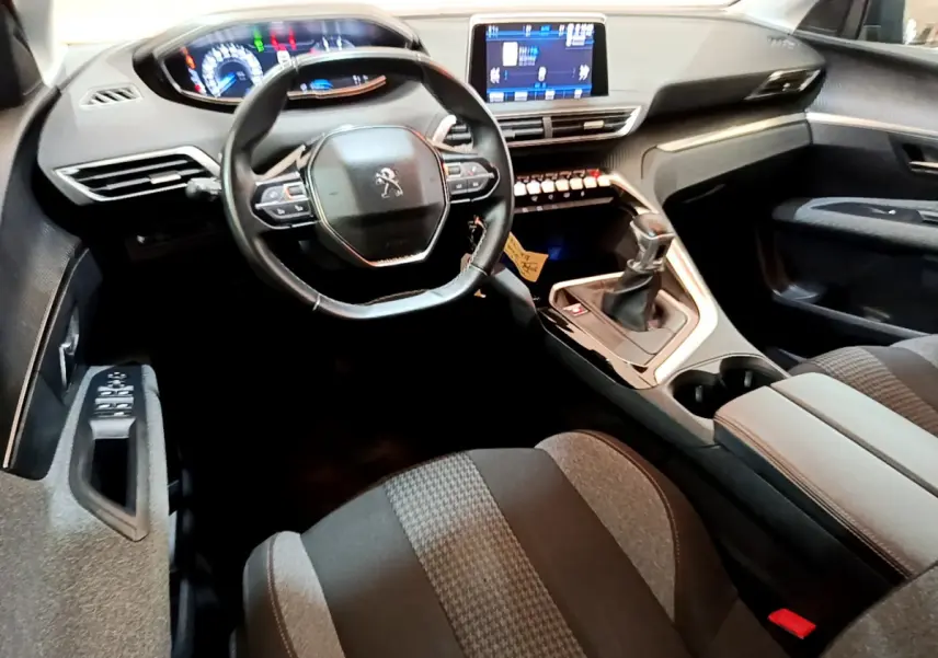 Vue intérieure du poste de conduite du Peugeot 3008 noir, avec volant compact, écran tactile central et levier de vitesses manuel.