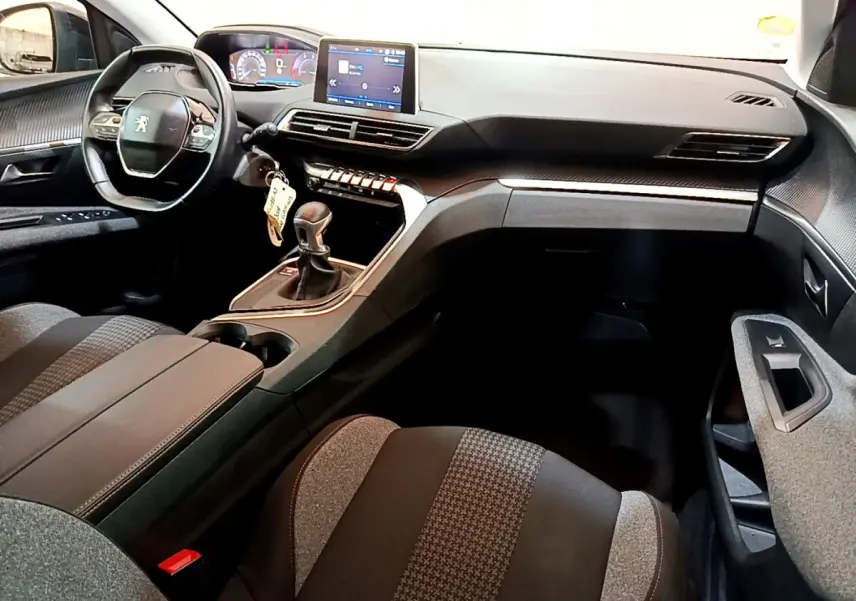 Intérieur du Peugeot 3008 2019, vue côté conducteur, tableau de bord noir avec écran tactile et volant cuir compact.