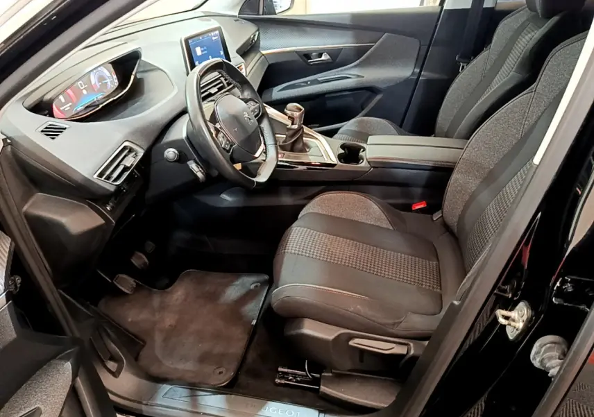 Intérieur avant droit du Peugeot 3008 noir 2019, volant cuir, tableau de bord numérique et sièges tissu gris.