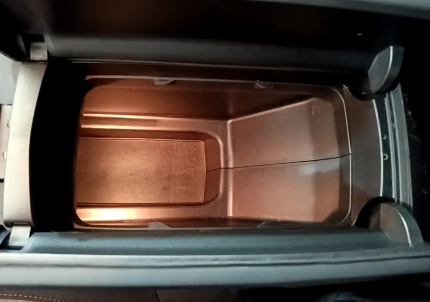 Gros plan sur le rangement central intérieur du Peugeot 3008 noir, montrant un espace vide et propre sous l'accoudoir.