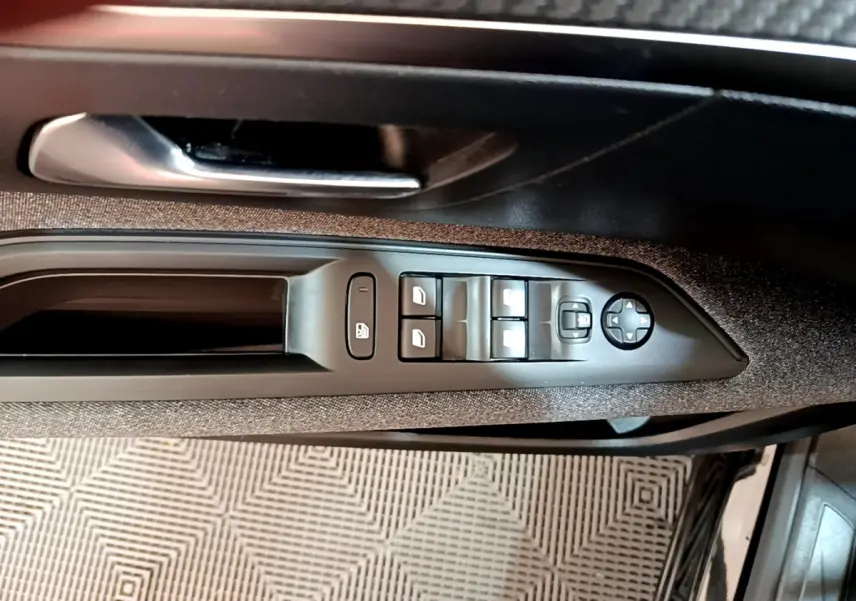 Gros plan sur la commande des vitres et rétroviseurs côté conducteur du Peugeot 3008 noir, intérieur tissu gris.