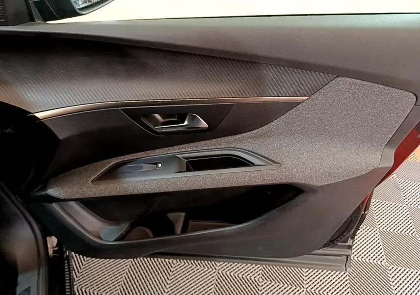 Gros plan sur la porte côté gauche du Peugeot 3008 noir, mettant en valeur la texture grise et la poignée intérieure métallique.