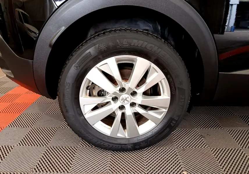 Gros plan sur la roue avant droite d'un Peugeot 3008 noir, avec jante alliage et pneu Michelin hiver.