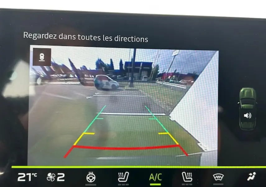 Vue caméra de recul du Dacia Duster III kaki dusty, affichant les lignes de guidage colorées et l'environnement arrière du véhicule.