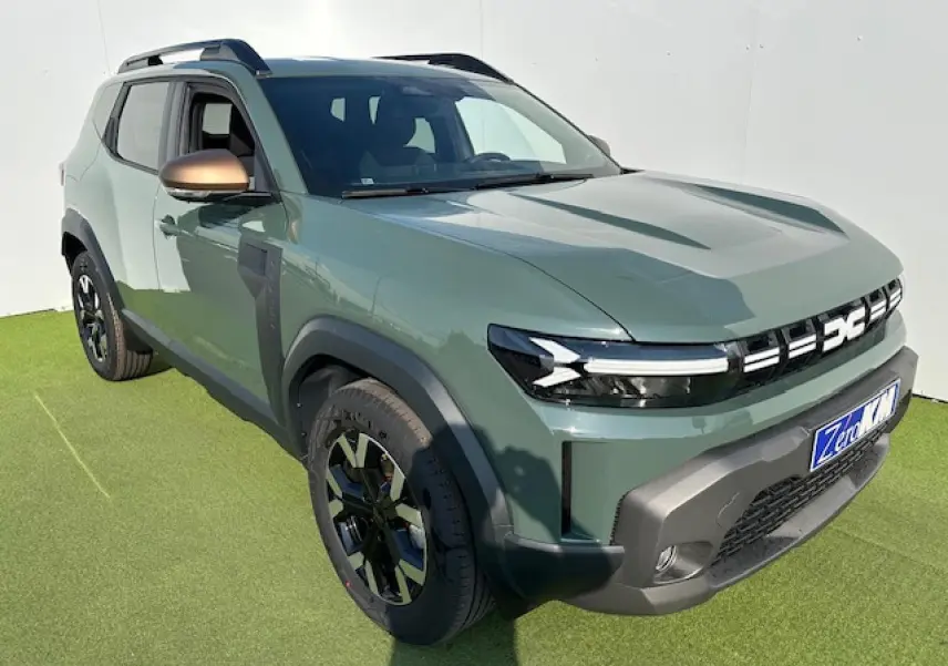 Dacia Duster III kaki dusty en 3/4 avant droit, avec jantes alliage noires et barres de toit longitudinales noires.