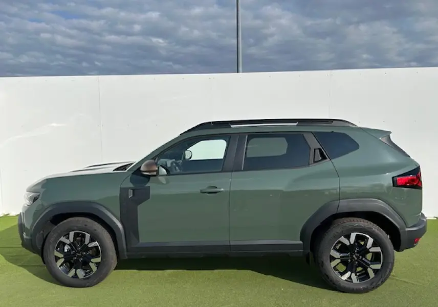 Profil côté gauche du Dacia Duster III 1.6 Hybrid 140 4x2 en kaki dusty avec jantes alliage et barres de toit noires.