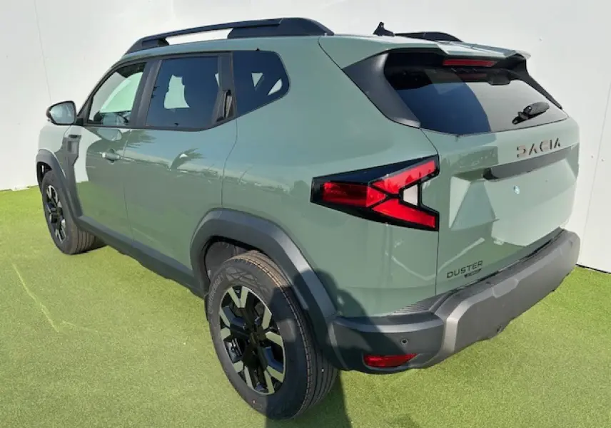 Vue 3/4 arrière droite du Dacia Duster III hybride en kaki dusty avec barres de toit noires et jantes alliage 17 pouces.