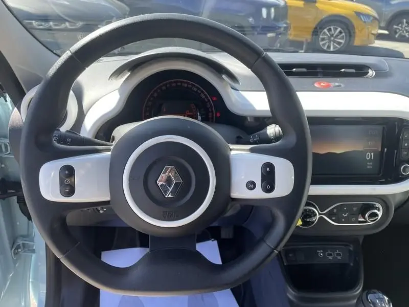 Vue intérieure centrée sur le volant noir et blanc de la Renault Twingo III 2022, avec tableau de bord et écran tactile visibles.