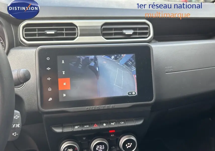 Intérieur du Dacia Duster 2024 noir, vue sur l’écran central tactile affichant la caméra de recul et la console de climatisation.