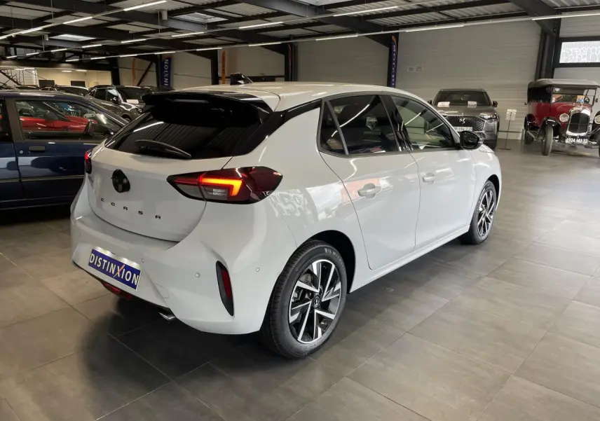 Opel Corsa blanche vue 3/4 arrière droit en intérieur avec feux arrière LED et jantes alliage diamantées.