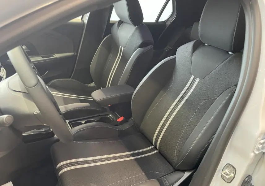 Vue intérieure côté conducteur de l'Opel Corsa 2026 blanche, sièges sport noirs avec bandes blanches centrales.