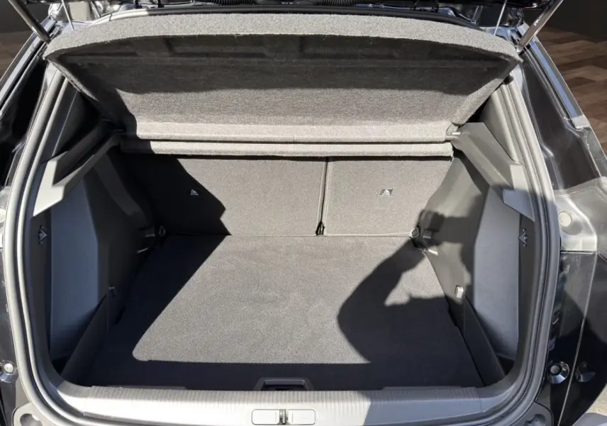 Coffre ouvert vu de dessus d’un Peugeot 2008 Hybrid 145 e-DCS6 GT noir, espace de rangement vide et propre.