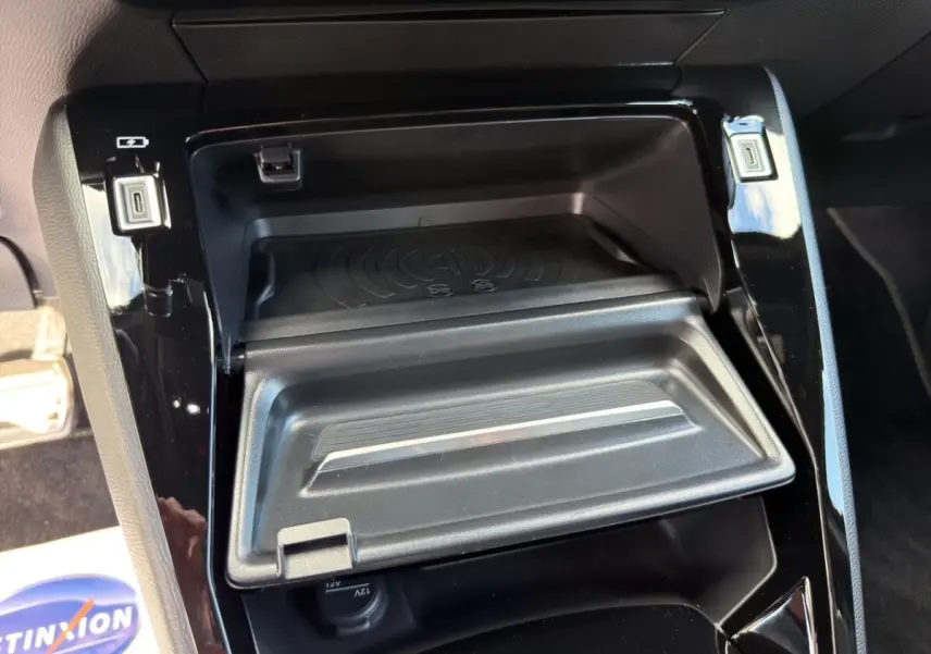 Vue rapprochée de la console centrale noire du Peugeot 2008 Hybrid 145 e-DCS6 GT avec rangement et ports USB visibles.