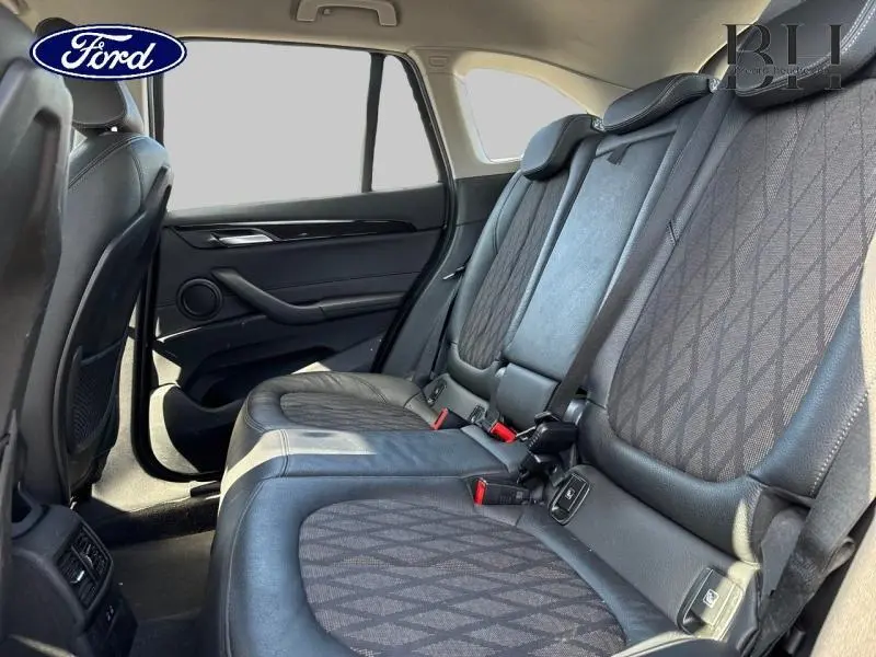 Vue intérieure côté droit des sièges arrière en cuir noir et tissu à motifs du BMW X1 xDrive25eA 2021.