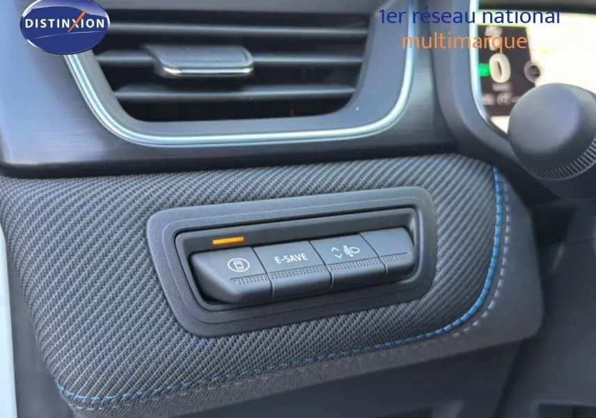 Détail intérieur du tableau de bord du Renault Captur blanc nacré, montrant les boutons de commande sur revêtement texturé gris.