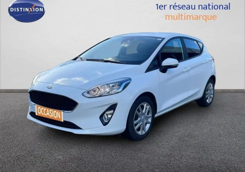 Ford Fiesta blanche vue en 3/4 avant droit, avec jantes classiques et vitres surteintées.