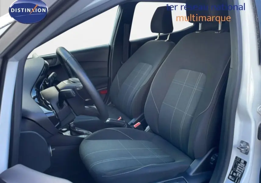 Vue intérieure côté conducteur de la Ford Fiesta blanche 2020, sièges tissu gris à motifs et tableau de bord moderne.