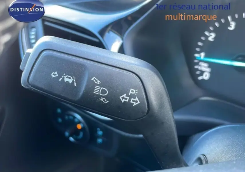 Gros plan sur le commodo de clignotants dans l’habitacle d’une Ford Fiesta blanche de 2020, avec tableau de bord en arrière-plan.