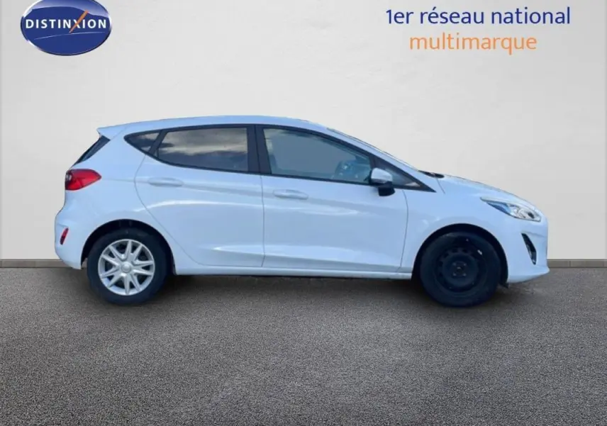 Profil droit d'une Ford Fiesta blanche 2020 avec vitres surteintées et jantes classiques, roue avant en acier noir.