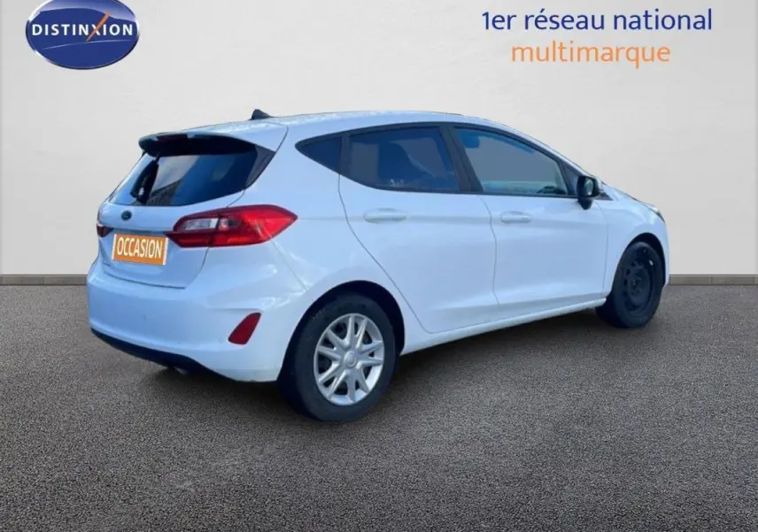 Vue 3/4 arrière droite d'une Ford Fiesta blanche avec vitres surteintées et jantes classiques 15 pouces.