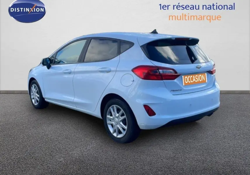 Vue 3/4 arrière droite d'une Ford Fiesta blanche avec vitres surteintées et jantes classiques 15 pouces.