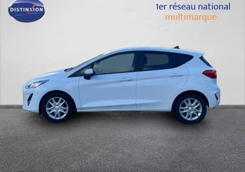 Vue de profil côté gauche d'une Ford Fiesta blanche 2020 avec vitres surteintées et jantes classiques 15 pouces.