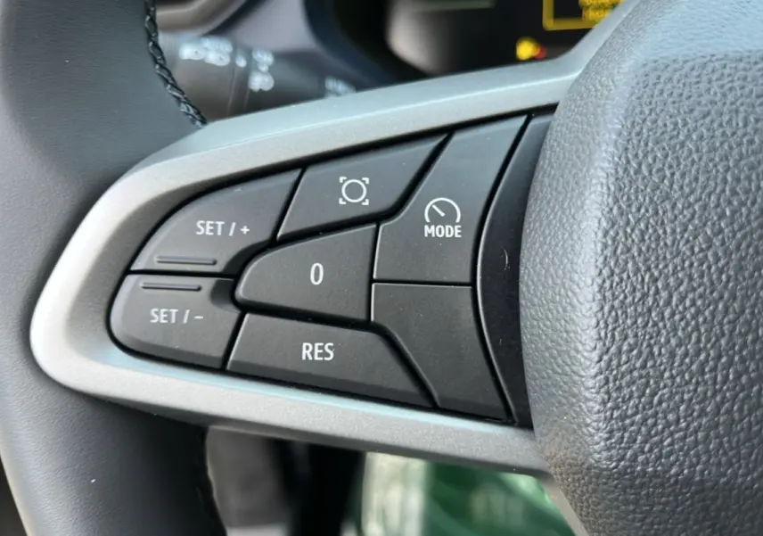 Gros plan sur les commandes de régulateur de vitesse au volant cuir du Dacia Bigster Hybrid 155 Expression Plus.