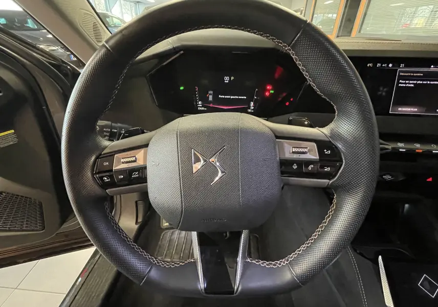 Volant cuir DS avec commandes intégrées, tableau de bord numérique et écran central dans un DS4 gris platinium 2024.