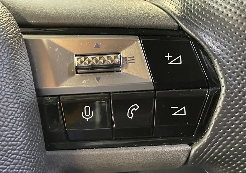 Gros plan sur les commandes du volant cuir perforé d'une DS4 gris platinium, boutons de volume et appels visibles.