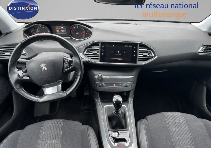 Vue intérieure avant de la Peugeot 308 2020, tableau de bord et volant noir avec levier de vitesse manuel.