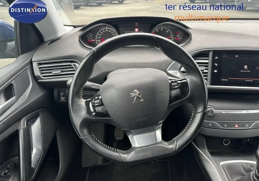 Vue intérieure centrée sur le volant cuir noir et le tableau de bord de la Peugeot 308 Bleu Magnetic de 2020.