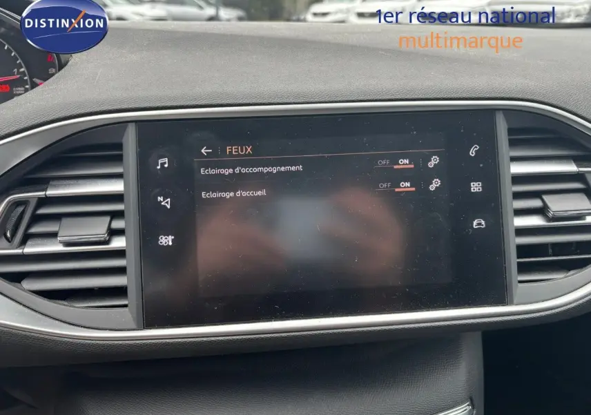 Écran tactile central du tableau de bord de la Peugeot 308 Bleu Magnetic, affichant les réglages des feux d’éclairage d’accompagnement et d’accueil.