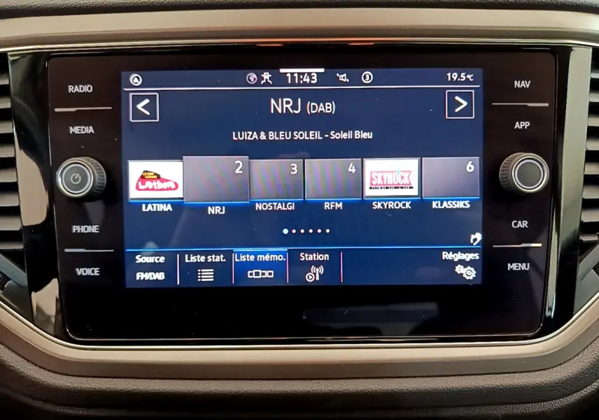 Écran tactile central du Volkswagen T-Roc blanc 2021 affichant les stations radio DAB, vue frontale rapprochée.