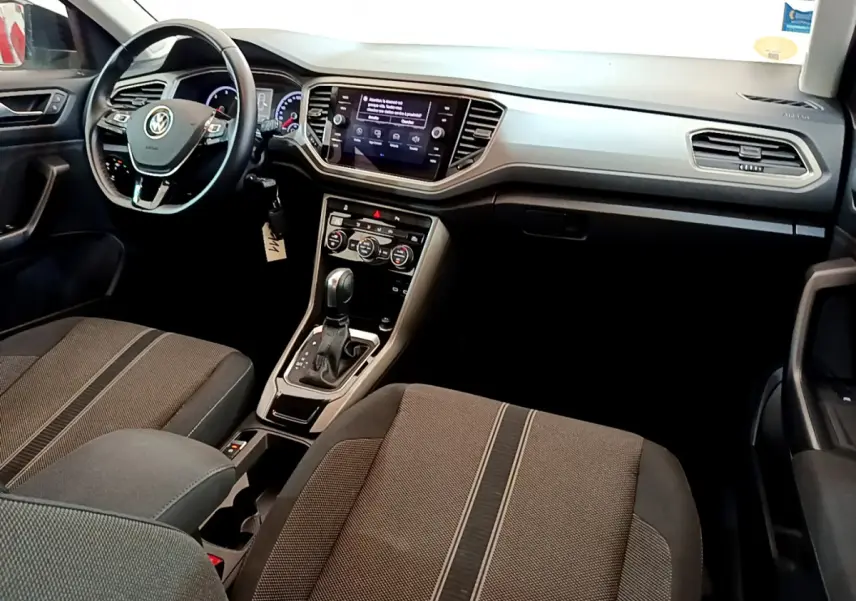 Intérieur Volkswagen T-Roc 2021 vu côté conducteur, tableau de bord moderne avec écran tactile et sièges tissu gris.