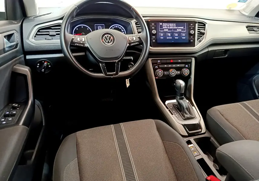 Vue intérieure avant du Volkswagen T-Roc 2.0 TDI blanc, avec volant multifonction, écran tactile et levier de boîte automatique.